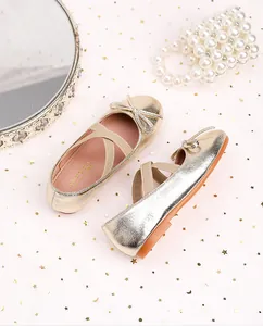 Detail of champagne gold ballet flats with cross straps and bow for girls' party wear