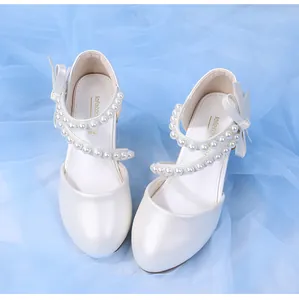 Close-up of pearl straps and silk bow details on white leather girl's princess shoes