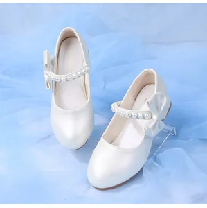 Detail of white girls princess shoes with pearl strap and elegant silk bow decoration