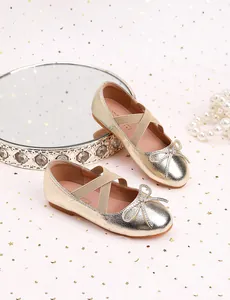 Macro shot of champagne gold girls princess shoes with bow detail and elastic straps