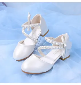 Detail of white pearlescent girls shoes featuring pearl straps and bow accents
