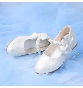 Macro shot of white girls princess shoes with pearl buckle and elegant bow details