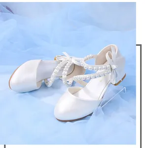 Detail of white girls princess shoes featuring multi-layer pearl straps and bow accent