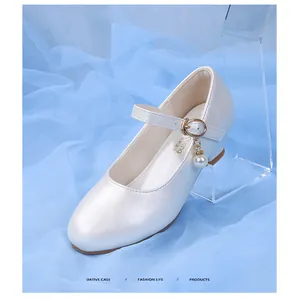 Détail de chaussure Mary Jane blanc nacré avec pendentif perle et bride à boucle