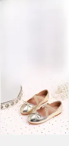 Detail of gold metallic girls flat shoes with bow and elastic straps for pageant wear