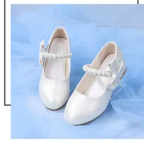Detailed view of pearl-beaded strap and decorative bow on white girls Mary Jane shoes