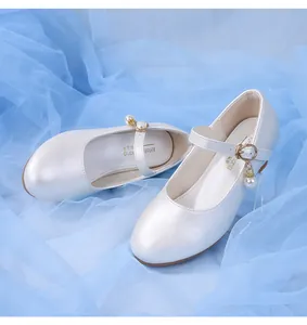 Détail de chaussure Mary Jane blanche avec pendentif perle élégant et bride à boucle réglable