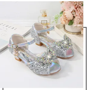 Close-up of girls silver glitter high heel sandals with sparkling rhinestone bow detail