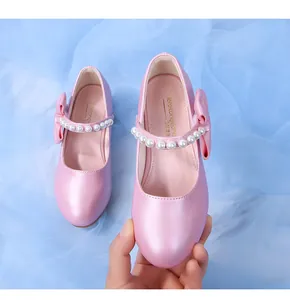Detailed shot of pearly pink Mary Jane shoes with pearl strap and bow on blue tulle