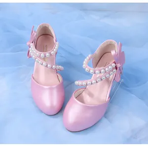Detail of pink pearlescent girl shoes with elegant pearl straps and a silk bow decoration