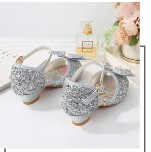 Detalle de zapatos de princesa plateados con lentejuelas, lazo grande y colgante de perla