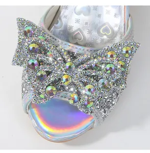 Close-up of glittery silver girls sandals featuring AB rhinestones and large bow detail