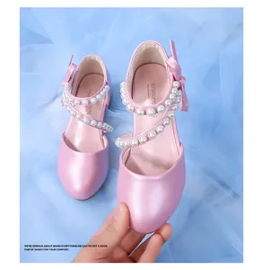 Detail view of pink Mary Jane shoes with pearlescent finish, double pearl straps and bow