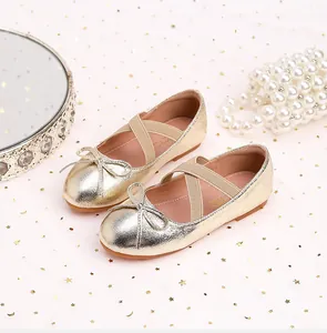 Close-up of golden metallic girls princess shoes with bow detail and elastic cross straps