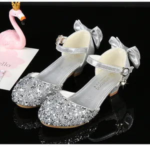 Détail de chaussures de princesse à paillettes argentées avec nœud et pendentif cœur