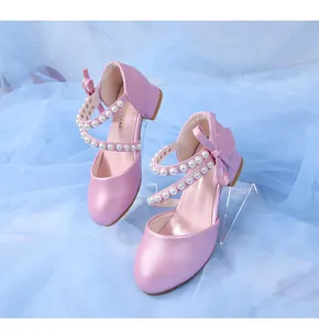 Detail of pink pearly princess shoes with pearl straps and bow on a blue background