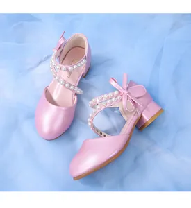 Detail of pink glossy Mary Jane shoes with pearl straps and bow decoration for girls