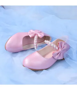 Detailed view of pink princess shoes with a pearly bow and shimmering leather finish