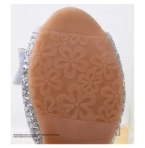 Close-up of brown rubber sole with floral anti-slip pattern on silver sequin girl shoes