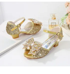 Detalle de sandalias doradas con lentejuelas para niña con lazo grande y perlas finas