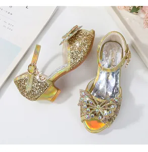 Detail of girls gold glitter sandals featuring a rhinestone bow and star moon pendant