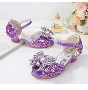 Detalle de sandalias moradas de lentejuelas para niña con lazo de perlas y un colgante