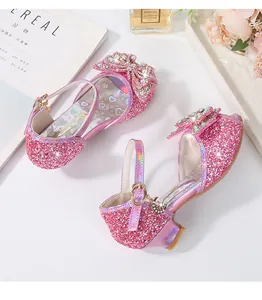 Detail of pink sequin girls' heels with a large rhinestone bow and gold buckle charm
