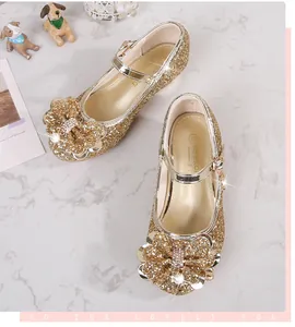 Dettaglio di scarpa da principessa in paillettes dorate con fiocco scintillante e perla