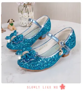 Dettaglio di scarpe da principessa con paillettes blu, fiocco di strass e pendente