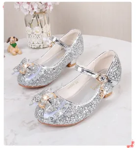 Macro detail of silver glitter girls Mary Jane shoes with rhinestone bow and heart charm