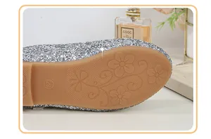 Detailed view of non-slip floral pattern on brown rubber sole of silver sequin shoes