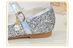 Detail of silver sequin Mary Jane shoe with iridescent strap and pearl charm accent