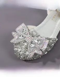 Close-up of silver sequin princess shoes featuring a large rhinestone bow detail