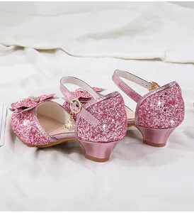 Close-up of pink sequin girl shoes with pearl bow decoration and rhinestone pendant