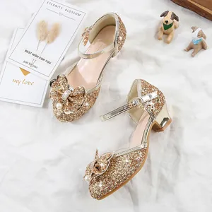 Close-up of girls' gold glitter Mary Jane shoes with sequin bow and pearl charm details