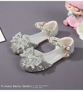Detailed view of silver sequin girl's sandals with rhinestone bow and pearl ankle strap