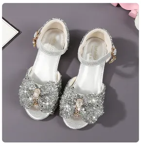 Close-up of girls silver sequin princess sandals featuring a large glittery bow with gold buckle