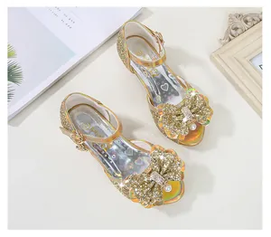 Detail of gold girls' princess sandals featuring rhinestone bow and pearl pendant