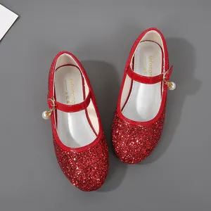 Detail of red sequined Mary Jane shoes with gold buckle and delicate pearl charm
