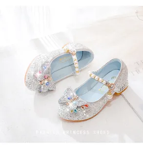 Détail de chaussures de princesse argentées à paillettes avec nœud strass et bride perle
