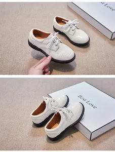 Détail de chaussures Oxford blanches pour garçons en cuir verni avec perforations et semelles