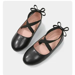 Detailed view of girls black matte ballet flats with elastic cross straps and heel bow