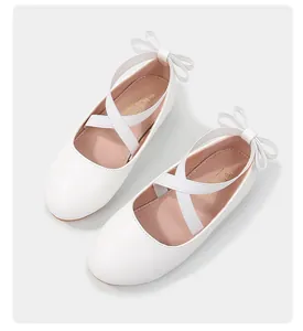 Close-up of white girls Mary Jane shoes with criss-cross straps and bow detail