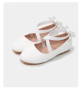Close-up of white Mary Jane shoes with cross elastic straps and back bow detail