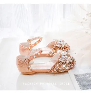 Détail de chaussures princesse fille or rose avec paillettes et nœud en strass brillant