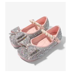 Detalle de zapatos de princesa plateados con purpurina para niña con perlas y un lazo