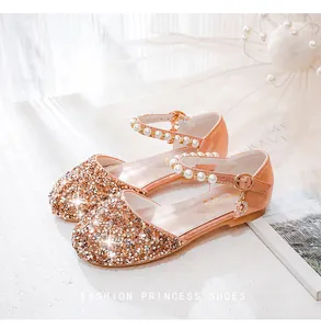 Detail von roségoldenen Pailletten-Prinzessin-Schuhen mit Perlenriemen und Mondanhänger
