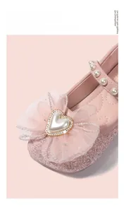 Dettaglio scarpe Mary Jane rosa glitterate con fiocco in rete e fibbia a cuore