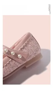 Dettaglio di scarpa da principessa rosa con paillettes e cinturino di perle