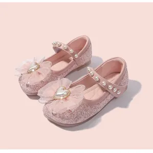 Dettaglio di scarpe da principessa rosa con paillettes, fiocco e cinturino di perle